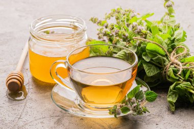 Nane melissa ve bal gri arka plan taze yaprakları ile çay içeceği fincan. Şifalı bitkisel içecek. Yatay çerçeve.