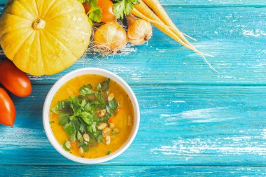 Kabak ve taze sebze çorbası beyaz kase yakın çekim ahşap mavi arka plan. Doğal rustik tarz. Üst görünüm düz yatıyordu.
