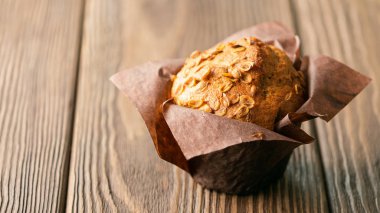 Kahverengi kağıt ambalaj yakın çekim ahşap arka plan buğday gevreği ile Muffins. Sağlıklı vegan tatlısı. Yatay çerçeve.