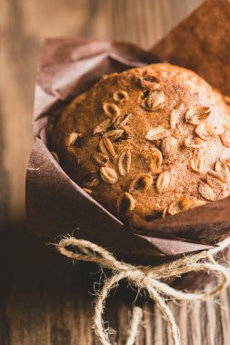Kahverengi kağıt ambalaj buğday gevreği ile Muffins yakın-up ahşap bir arka plan. Sağlıklı vegan tatlısı. Dikey çerçeve.