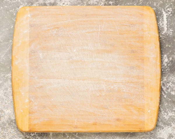 Wooden cutting board sprinkled with empty flour on a gray background. Copy space. Template for text or design. Top view — Stock Photo, Image