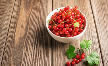 Ahşap bir arka planda beyaz bir bardak taze Olgun kırmızı frenk üzümü Berry. Yatay çerçeve.