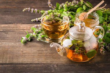 Ahşap rustik bir arka plan üzerinde bir fincan ve çaydanlık limon balsam nane taze yaprakları ile Çay. Şifa bitkisel içecek.