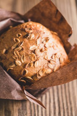 Kahverengi kağıt ambalaj yakın çekim ahşap arka plan buğday gevreği ile Muffins. Sağlıklı tatlı. Dikey çerçeve. Renklendirme
