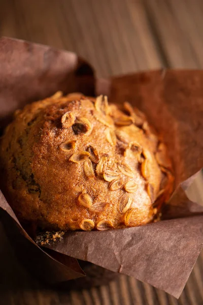 Kahverengi kağıt ambalaj yakın çekim ahşap arka plan buğday gevreği ile Muffins. Sağlıklı vegan tatlısı. Dikey çerçeve