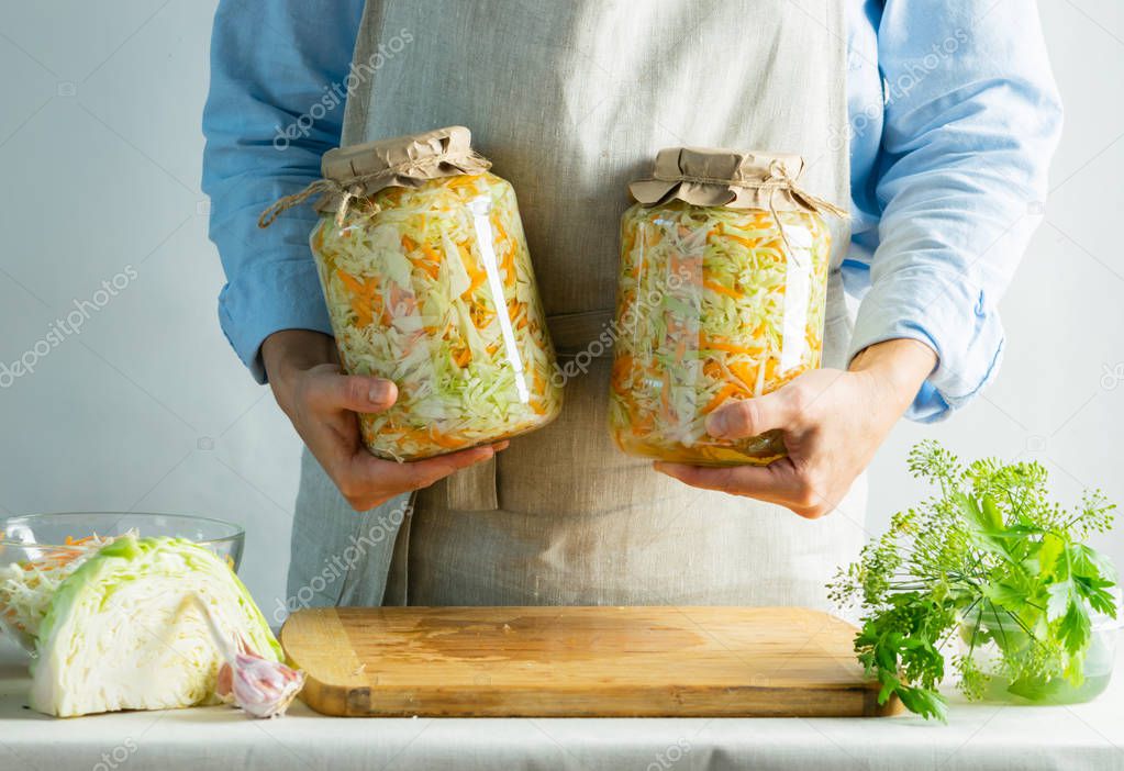 Fermentation preservation Sauerkraut in glass jars in the hands of a woman natural background. Canned food concept.