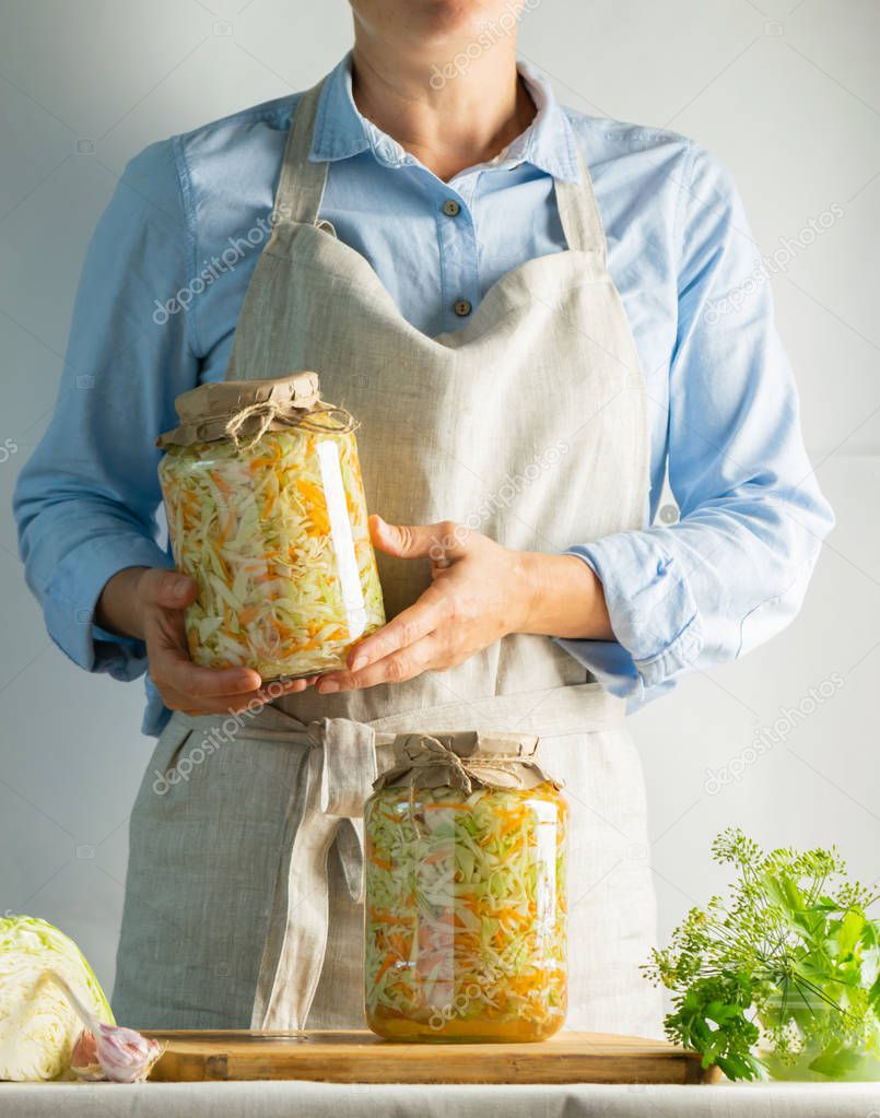 Fermentation preservation Sauerkraut in glass jars in the hands of a woman natural background. Canned food concept.