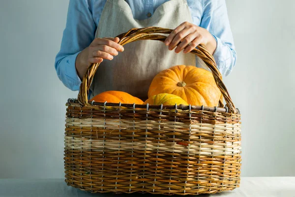 Masada kabak mahsulü olan büyük bir sepet. Kadın elleri onu tutuyor. Rustik doğal stil. Hygge akraba tarzı