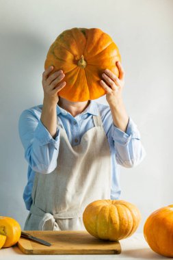 Hafif bir pamuk önlük kadın aşçı yerine bir baş büyük bir olgun kabak tutar. Gıda kavramı şaka.