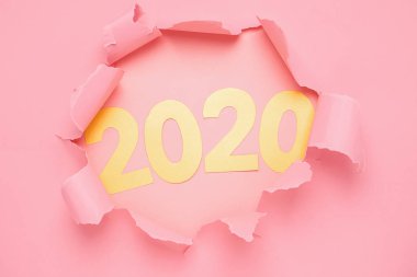 2020 sayısının yeni yılı ve pembe kağıt arka plan üzerinde bir delik sembolü. Yırtık kağıt minimalizmi. Yeni Yıl konsepti.