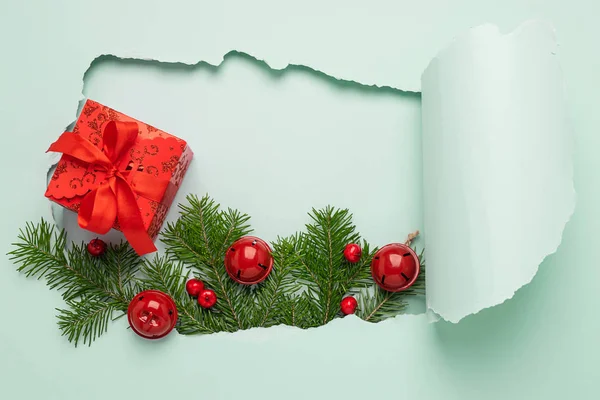 Neujahr Layout Loch Papier Hintergrund mint Farbe. Weihnachtsbaum Spielzeug Zweige Geschenk mit roter Schleife blau hell Hintergrund. — Stockfoto