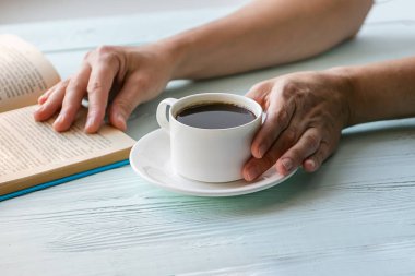 Bir fincan siyah klasik kahve ve kadın elinde kitap. Seçici odak. Kopya alanı. Yatay çerçeve.