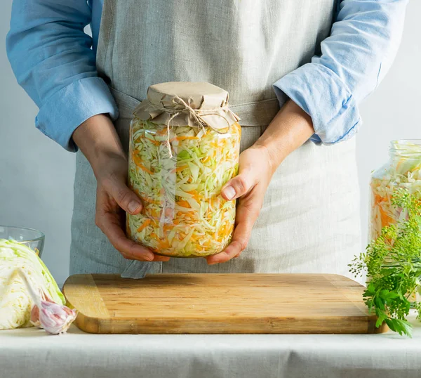 Conservación de la fermentación Sauerkraut en frascos de vidrio en las manos de una mujer de fondo natural. Concepto de comida enlatada . — Foto de Stock