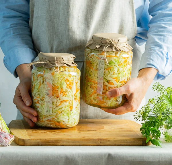 Fermentation preservation Sauerkraut in glass jars in the hands of a woman natural background. Canned food concept. — Stock Photo, Image