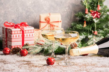 Zarif cam kadehlerde şampanya, hediyeli şenlikli Noel masası ve süslü Noel ağacı. Yeni yıl konsepti.