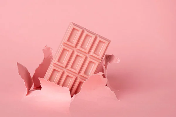 Telhas de chocolate rosa no fundo pastel contra o fundo de papel de explosão buraco. O conceito de comida é minimalismo . — Fotografia de Stock