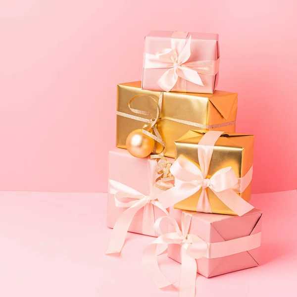 Cajas rosadas doradas festivas con bolas de juguete de lazo de raso sobre un fondo rosa pastel. Concepto de vacaciones . —  Fotos de Stock