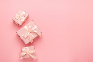 Pastel pembe arka planda saten kurdeleli tatil kutuları. Şen minimalizm konsepti. Düz biçim düzeni.