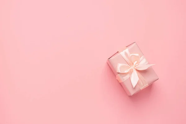 Feestelijke geschenkdoos met satijnen strikje op een pastelroze achtergrond. Feestelijke minimalisme concept. Platte lay-out. — Stockfoto