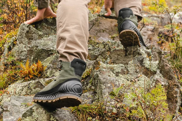 Hiking boots on rock. Mens feet in boots on natural stones. Travel and adventure concept