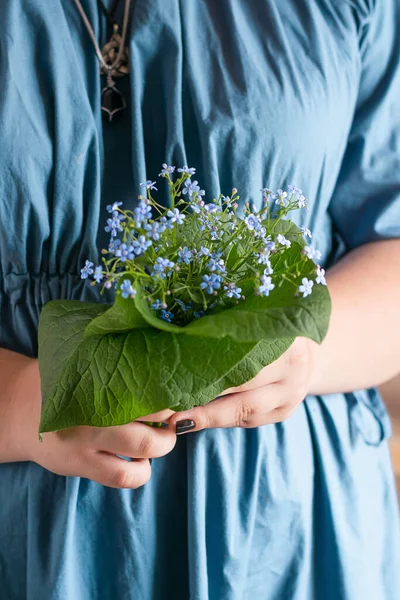 Pequeño ramo lindo de flores rústicas frescas en manos femeninas. Una mujer con un vestido azul sostiene flores frescas. Primer plano — Foto de Stock