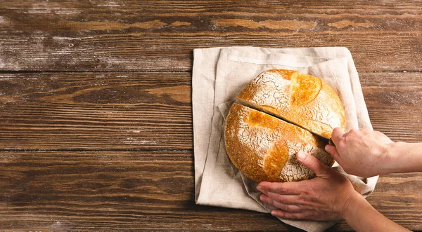 Kobieta trzyma w rękach bochenek świeżo krojonego chleba w rustykalnym tle. Koncepcja domowego pieczenia dietetycznego bez — Zdjęcie stockowe