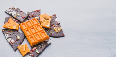 Çikolata renginde portakal renkli meyveler dilimlerle süslenmiş fındıklar ve gri arka planda dilimler. Küçültme