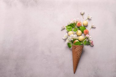 Beyaz çikolatalı yer mantarı çiçekli waffle külahlı dondurma, gri beton arka planda. Yatay çerçeve kopyalama alanı.