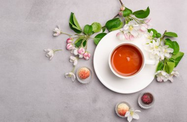 Şenlikli zarif bir kutuda çeşitli renkte çikolatalar. Pastel pembe arka plan dekorasyon çiçeklerinde bir fincan çay paketliyorlar..