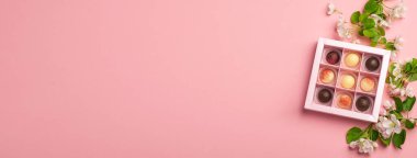 Pembe arka planda bir kutuda çikolata şekeri. Tatil konsepti. Minimalizm yemek tatlısı. Yatay çerçeve