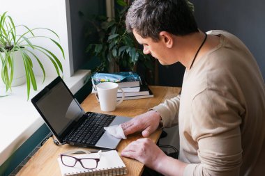 Bir kadın, koronovirüs gribini önlemek için laptopunu ıslak alkolle siler..