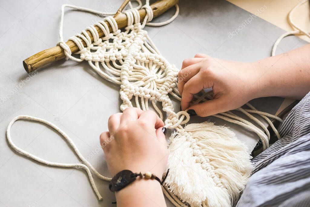 Female hands weave macrame in the home workshop. Boho lifestyle. Hobby hobby concept. Selective focus horizontal frame.