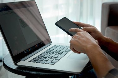 Evde, tatilde, çevrimiçi toplantılarda çalışmak bir dizüstü bilgisayar ve akıllı telefon kullanarak evden online bir iş yaratmak.