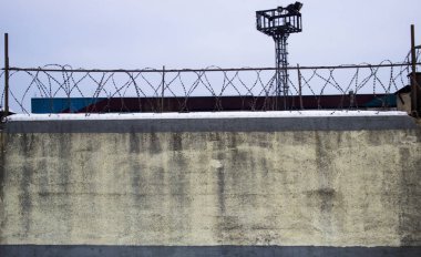 Gökyüzü ve gözlem kulesi karşı dikenli tel ile beton duvar. Kentsel.