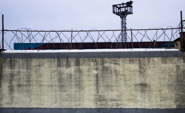 Gökyüzü ve gözlem kulesi karşı dikenli tel ile beton duvar. Kentsel.