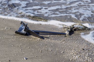 Kum üzerinde bağlı bir ip ile metal çapa