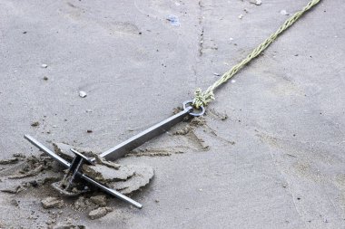 Kum üzerinde bağlı bir ip ile metal çapa