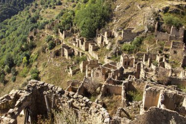 Şehir - hayalet, Dağıstan, Rusya - 1 Eylül 2019: Antik kalıntılar şehri, şehir - hayalet, arka plan kayalar üzerinde yeşil bitki örtüsü ile dağlık alan, mavi gökyüzü ve yeşil orman