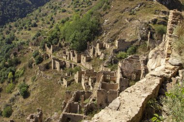 Şehir - hayalet, Dağıstan, Rusya - 1 Eylül 2019: Antik kalıntılar şehri, şehir - hayalet, arka plan kayalar üzerinde yeşil bitki örtüsü ile dağlık alan, mavi gökyüzü ve yeşil orman