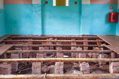 Kırık ahşap zemin, çürümüş ahşap zemin, tuğla sütunlar.