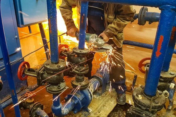 Male hand cuts off pieces of water pipe with angle grinder. Cutting of a steel with splashes of sparks inside. Sparks during cutting of metal angle grinder