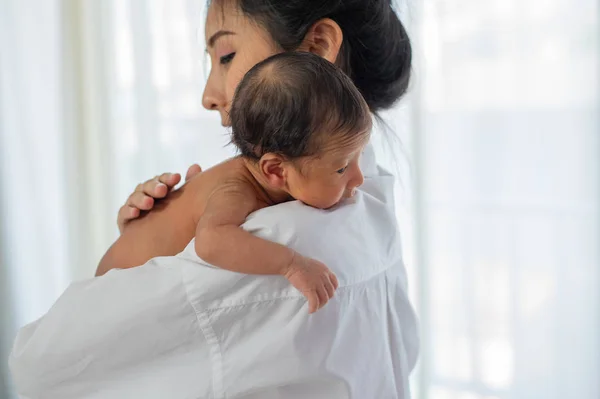 ミルクを与えた後 小さな新生児の肩に白いシャツを着たアジアの母親は眠そうに見える — ストック写真