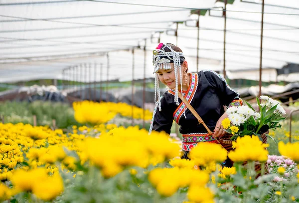 山部落女孩在花园里收集黄色的花朵 面带微笑 左手拿着篮子 — 图库照片