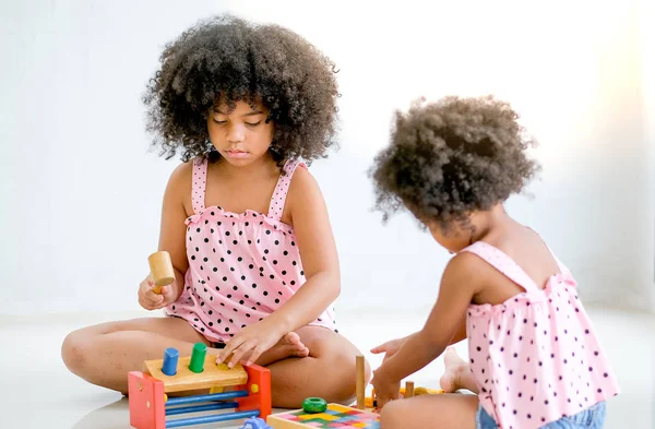 两个年轻的非洲女孩玩玩具一起主要集中在左侧的女孩谁看起来集中在她的玩具 — 图库照片