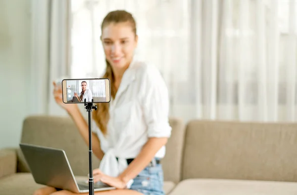 Beyaz gömlek gösterisi ve canlı inceleme online alışveriş konsepti ile cep telefonundan kamera önünde kozmetik ürün güzel kız.