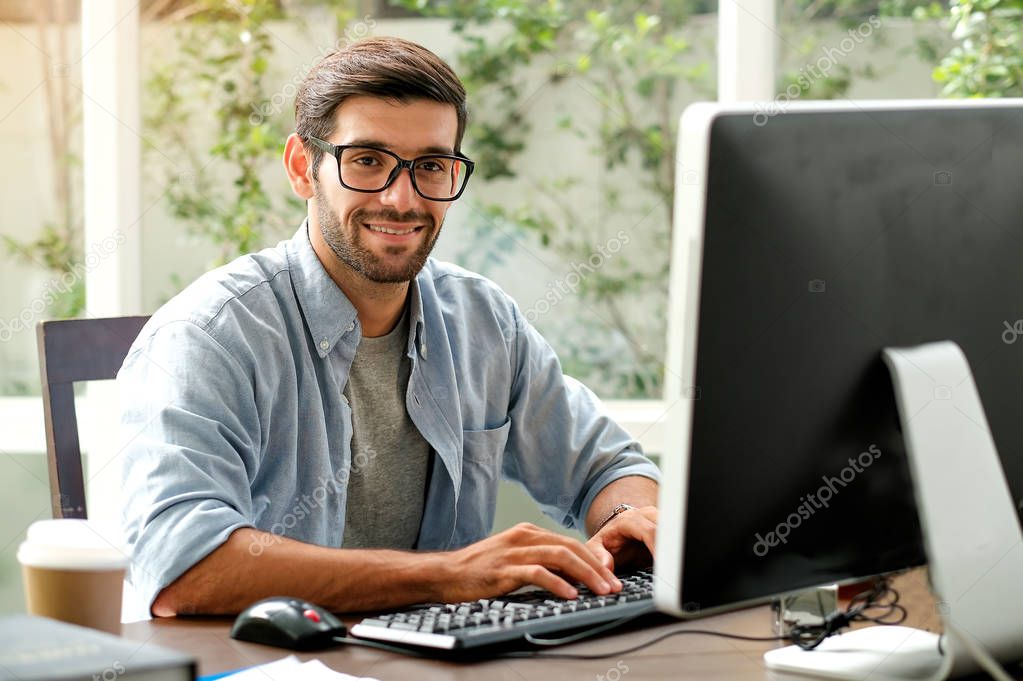 Handsome engineer man is typing computer on the table in the office with glass window.