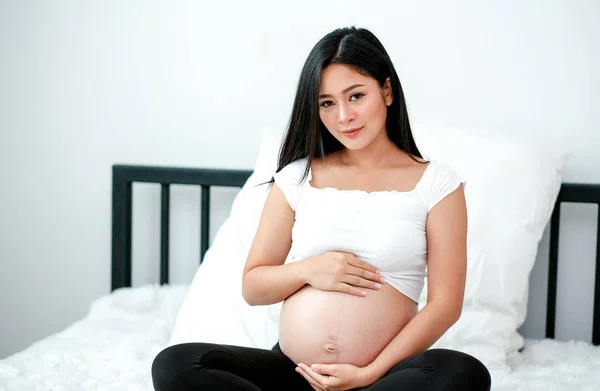 Asian Piękny Ciąży Kobieta Dotknąć Jej Brzuch Siedzieć Białe Łóżko — Zdjęcie stockowe