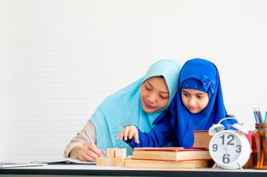 Müslüman anne ve mavi başörtüsü ile kızı beyaz perde ile odada birlikte oyuncak oynamak.