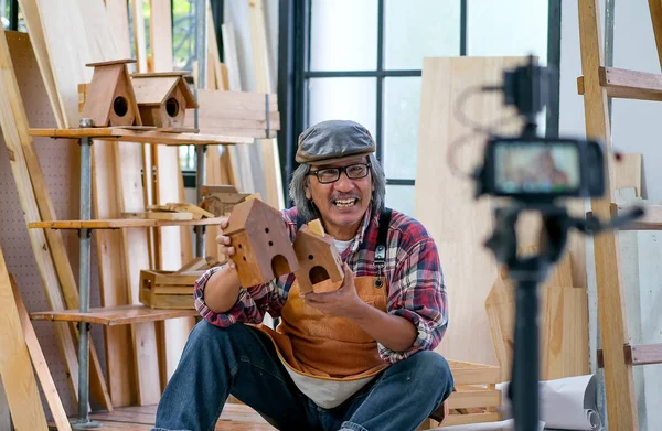 Asian old craftsman present his wood product in front of the camera and look like sell it online.