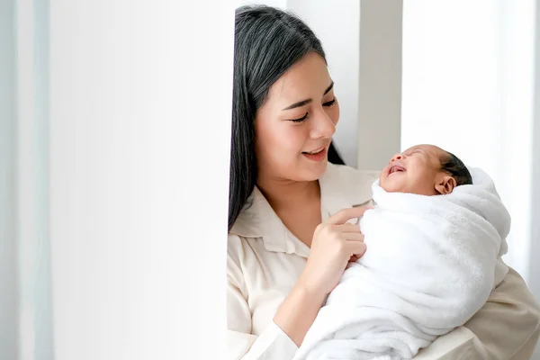 美しいアジアの母親は 愛の感情と赤ちゃんの笑顔で彼女の生まれたばかりの赤ちゃんを見て 日の光と白いカーテンの前で — ストック写真